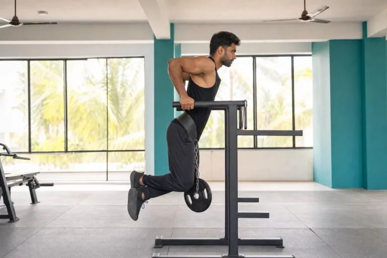 Muscular man doing weighted dips in a gym